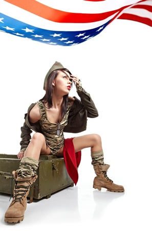 Young attractive girl dressed in old battle coat sitting . Vintage style studio shot.の写真素材