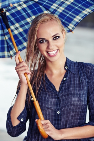 Sexy girl under umbrella watching the rainの写真素材
