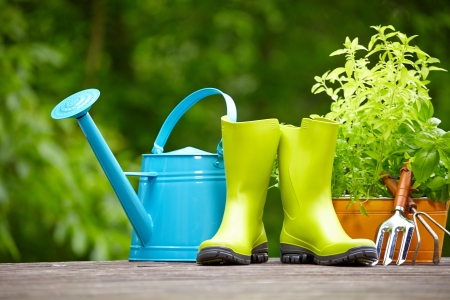 Rubber boots with watering can in wood terraceの写真素材