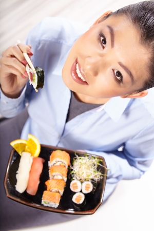 Beautiful young woman eating sushiの写真素材