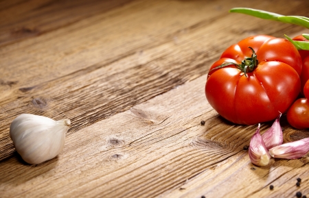 Red tomatoes with pepper and garlic on old wooden tableの写真素材
