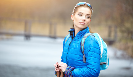 Closeup of young woman with Nordic walking poles in spring village