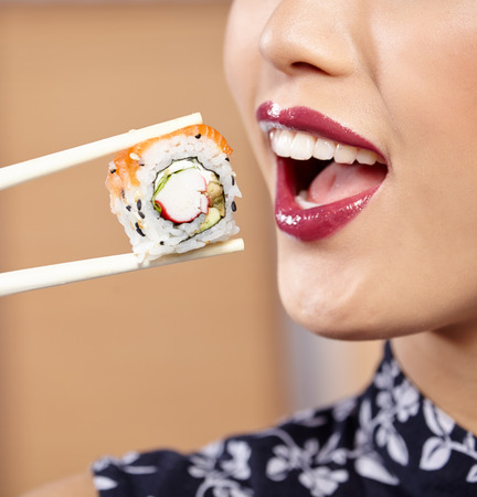 beautiful asian woman eating sushi with chopsticksの写真素材