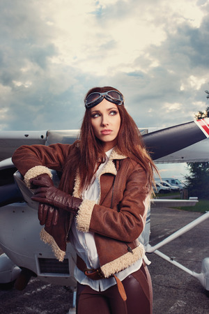 Portrait of young beautiful woman pilot in front of airplane. の写真素材