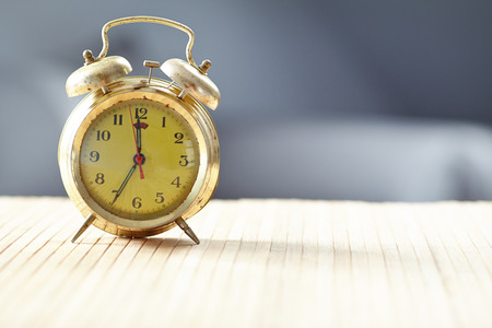 Retro alarm clock on desk front grey wall background の写真素材
