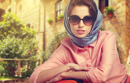 Elegant woman with a suitcase travel on street of italian cityの写真素材
