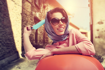 Elegant woman with a suitcase travel and ticket on street of italian cityの写真素材