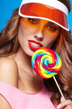 Beauty summer model girl Eating colourful lollipop on blue backgroundの写真素材