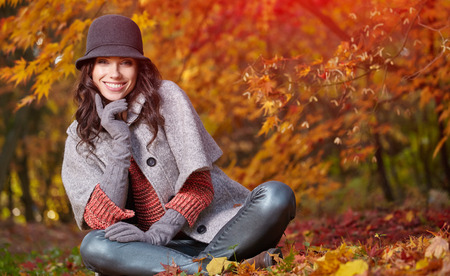 Young woman with autumn leaves in hand and fall yellow maple garden backgroundの写真素材