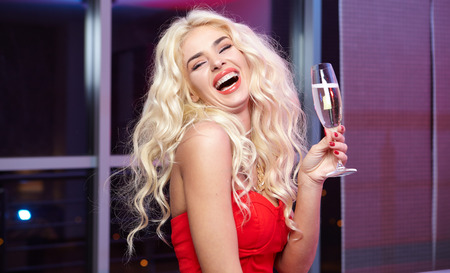 smiling woman in red dress with a glass of champagneの写真素材