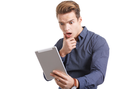 Young man Looking at a tablet, isolated in whiteの写真素材
