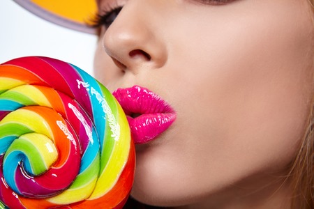 beautiful woman eating big  lollipop in sun hat on white backgroundの写真素材