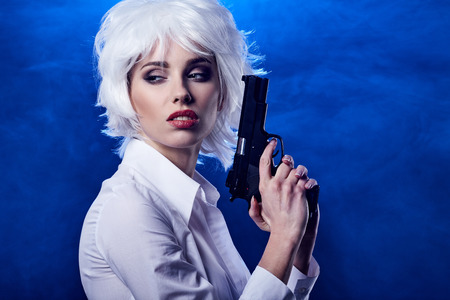 beautiful sexy girl holding gun . smoke backgroundの写真素材