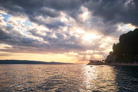 Rock island at sunset in small mediterranean town Brela , Croatiaの写真素材
