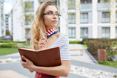 Young attractive happy student woman wearing  glasses holding a briefcaseの写真素材