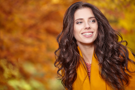 Beautiful young woman in autumn styling on the background of autumn parkの写真素材