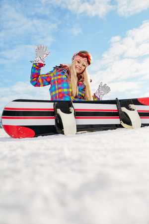 Young female snowboarder sitting on slopeの写真素材