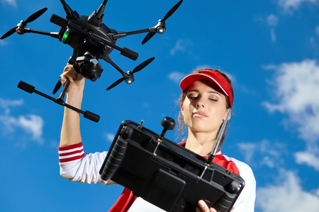 A woman is standing and holding drone