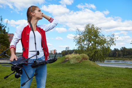 A brunette coed flying a drone in the outdoors