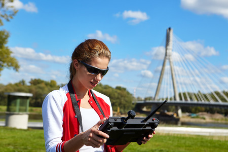 A brunette coed flying a drone in the outdoors