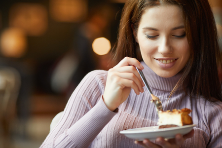 Beautiful woman eating chocolate cake at cafeの写真素材