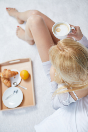 Young beautiful woman having breakfast in bed.の写真素材