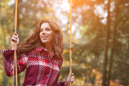 Woman on a swing in an autumn parkの写真素材