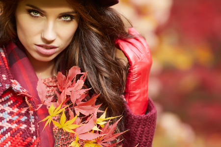 Portrait of an autumn woman over red and golden leavesの写真素材
