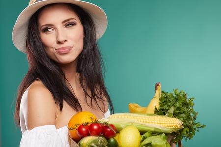 woman holding a grocery bag full of fresh and healthy food isolated on green backgroundの写真素材