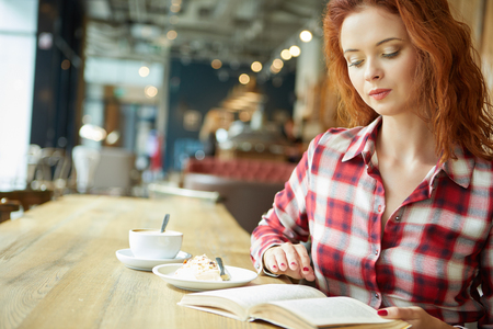 girl reading a book in a cafeの写真素材