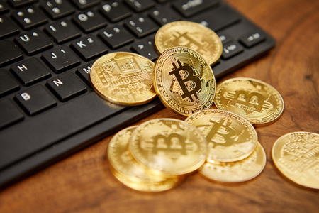 Golden bitcoins on a black computer keyboard の写真素材