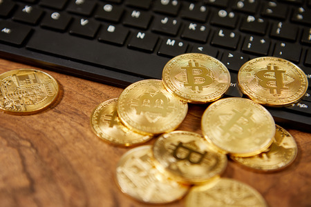 Golden bitcoins on a black computer keyboard の写真素材