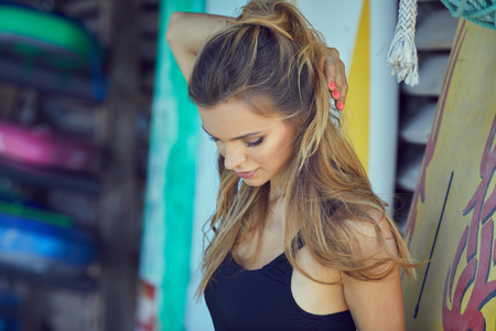 Surfing girl posing in the beach with surfboard