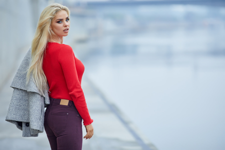 Gorgeous lady in red sweater poses before a riverの写真素材