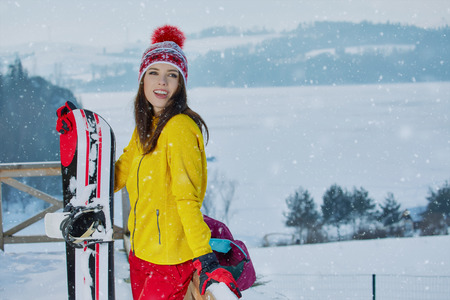 Sporty female holds snowboard in mountains