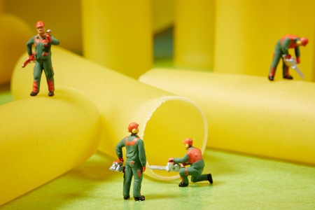 Miniature worker at work. Miniature worker work with spaghetti