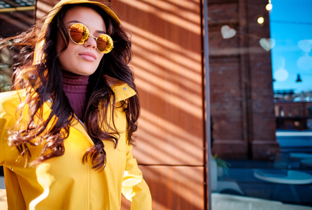 Attractive hipster young woman in stylish sunglasses in a stylish yellow coatの写真素材
