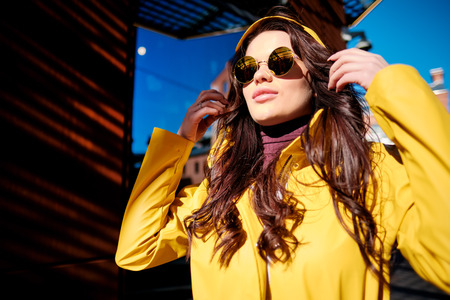 Attractive hipster young woman in stylish sunglasses in a stylish yellow coatの写真素材