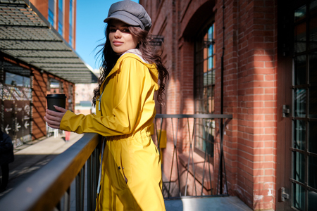 young woman in yellow raincoat at city streetの写真素材