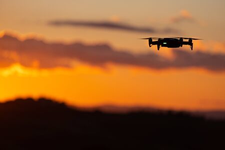 Flying silhouette of drone against sunset. Flying silhouette of drone against beautiful sunset skyの写真素材