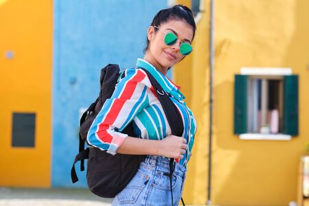 A girl with a backpack visits a colorful Italian town