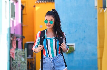 A girl with a backpack visits a colorful Italian town