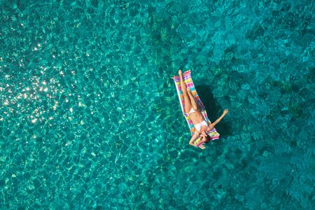 aerial view of a beautiful young woman in bikini on a matress in the seaの写真素材