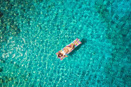 Turquoise ocean water and relaxed swimming woman, aerial drone shot.の写真素材