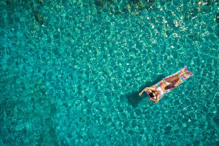 Aerial view of young woman swimming on the pink inflatable mattr.の写真素材
