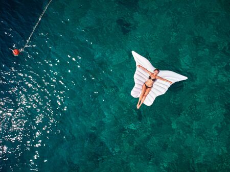 Turquoise ocean water and relaxed swimming woman, aerial drone shot.