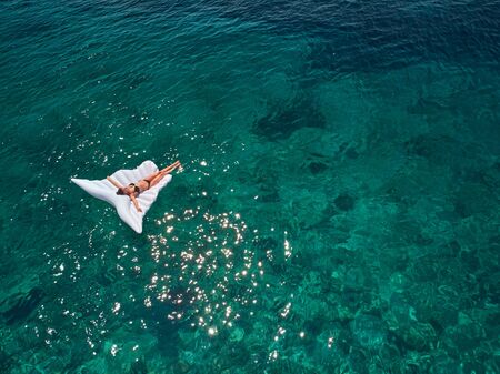 Turquoise ocean water and relaxed swimming woman, aerial drone shot.