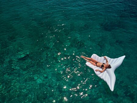 Turquoise ocean water and relaxed swimming woman, aerial drone shot.