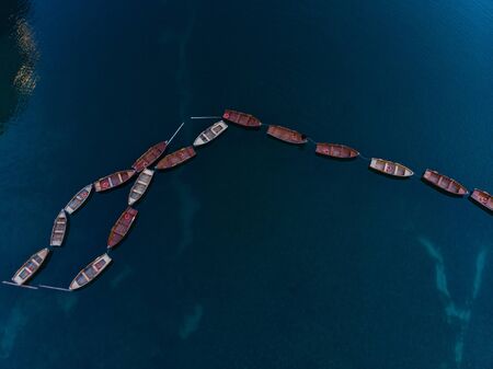 Aerial photo of a top down view of a more boats sailing in a beautiful blue lake