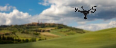 A flying drone with camera with blured hills of Tuscany in the backgroundの写真素材